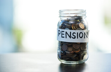 Save every dime and dollar. Shot of a pension money jar on a table at home.