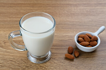 Almond milk in glass with almonds on the table. Space for text
