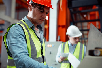 Chief engineer is looking at a work that he is making or checking security system setup at metal lathe industrial manufacturing.