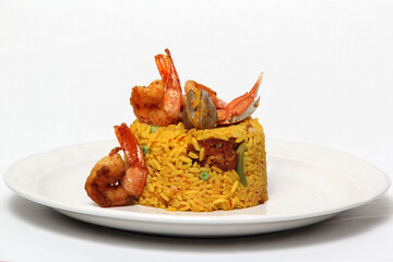 Paella rice is a traditional cuisine recipe from the city of Valencia Spain prepared with saffron, seafood, shrimp, vegetables served on a white plate
