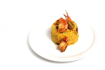 Paella rice is a traditional cuisine recipe from the city of Valencia Spain prepared with saffron, seafood, shrimp, vegetables served on a white plate
