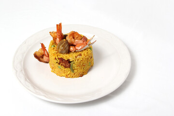 Paella rice is a traditional cuisine recipe from the city of Valencia Spain prepared with saffron, seafood, shrimp, vegetables served on a white plate

