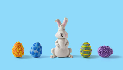 Easter greeting card with rabbit design and easter eggs lined up and centered. Handmade from plasticine on a blue background with copy space
