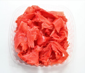 Pickled pink ginger in a plastic container. Portioned ginger for sushi.