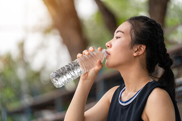 Asian young girl drinking water after jogging, healty and sport concept.