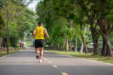 Fototapeta na wymiar Backside of senior man in fitness wear running in a park. Healthy lifestyle concept.