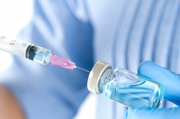 doctor's hand holds a syringe and a blue vaccine bottle at the hospital. Health and medical concepts.