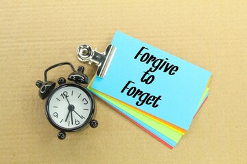 an alarm clock and colored paper with the words forgive to forget