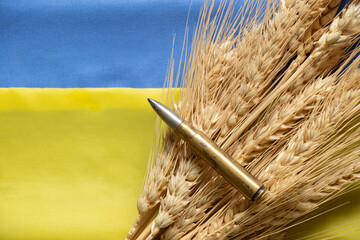 Ears of wheat and a bullet lie on the national flag of Ukraine, yellow and blue, Stop the war in...