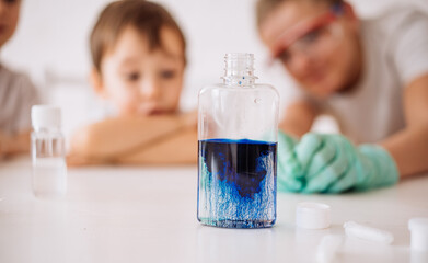 young children conduct experiments, children watch a bottle with blue granules. Early development of children. Research and development concept