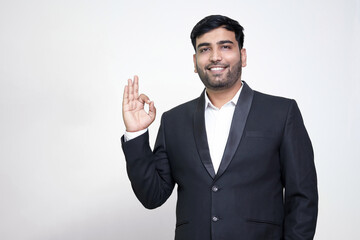 Portrait of a cheerful young man showing okay gesture isolated on the white isolated background.