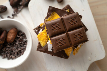 Raw Vegan Handmade Chocolate with dried mango fruits and coconuts slices close up. Chocolate bar with mango on a light background