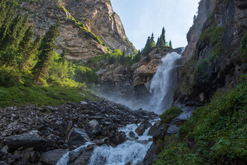 Beautiful waterfall in mountains with. Barskoon waterfall - splashes of Champaign. Travel, tourism in Kyrgyzstan concept.