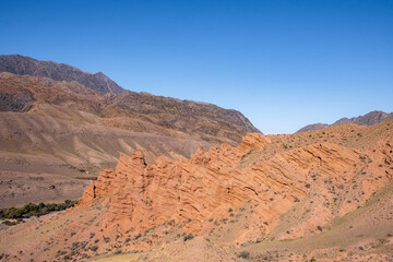 Fototapeta na wymiar Beautiful red clay mountains eroded on wind. Red mountains or red canyon on the way from Assy plateau to Bartogai reservoir. Mountain canyon landscape.