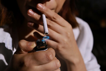 Obraz premium girl lighting a cigarette with a lighter in the evening
