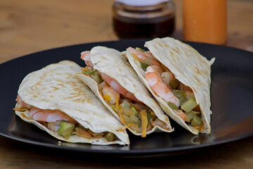 Un primer plano del burrito de tortilla de harina con las salsas en la mesa de madera