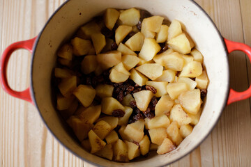 Top view of cut up apples and raisins cooked in a pot. Making apple-raisins filling.