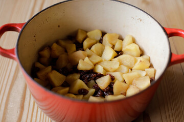 Fototapeta na wymiar Cut up apples and raisins cooked in a pot. Making apple-raisins filling.