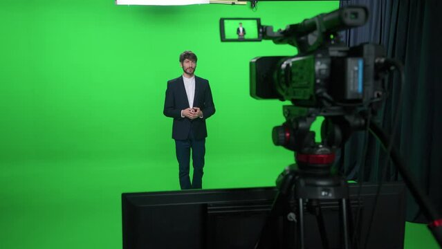 Backstage, news anchor at work, man reporter looks into the camera and talks, studio TV news shooting, chroma key template.