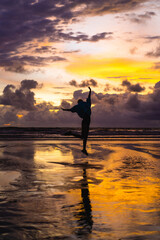 Beautiful young woman at sunset on the ocean, Bali, Indonesia.