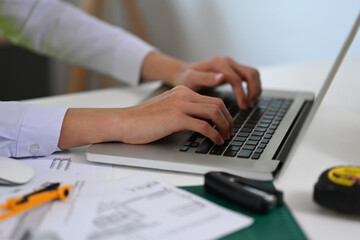 Fototapeta premium Engineer man hands typing on laptop computer while working on construction project.