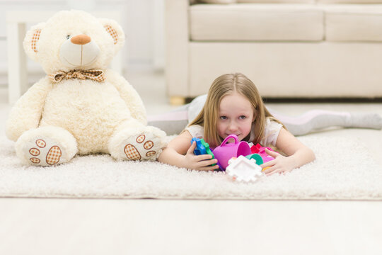 Photo of blond girl laying on the floor with toys.