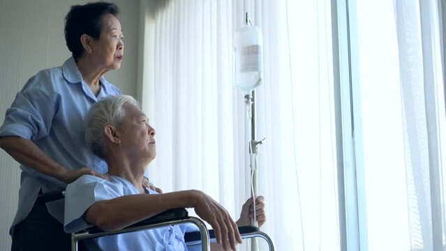 Wife Comforting Massaging Husband On Wheel Chair Worry Older Asian Elder Senior Couple In Hosital