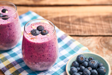 Blueberry smoothie in glass. Homemade blueberry smoothie on rustic wooden table. Blueberry smoothie with yogurt and oats.