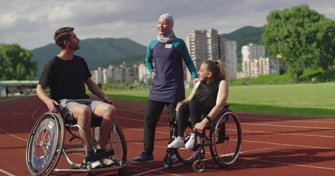 shot of disabled sport people whit female trainer wearing hijab after training on athletics sports track. 