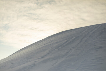 Mountain of snow. Snowy slope. Slide against sky.