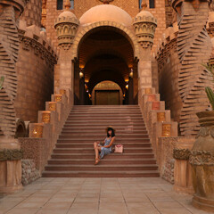 Fototapeta premium young girl on the background of the El Mustafa Mosque in the Old City of Egypt. woman sits on the steps of a mosque. Travel to Egypt concept. An ancient mosque in the tourist city of Sharm El Sheikh
