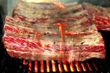 spice marinated american angus beef ribs on a barbecue grill with flame