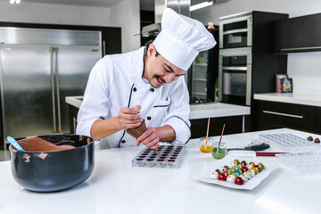 hispanic man pastry chef wearing uniform in process of preparing delicious mexican sweets chocolates at kitchen in Mexico Latin America