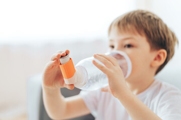 Boy inhales asthma medicine through homemade spacer. - obrazy, fototapety, plakaty