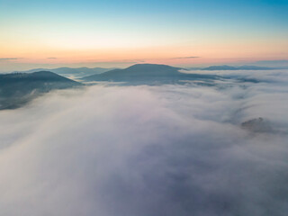 The rays of dawn over the fog in the Ukrainian Carpathians. Aerial drone view.