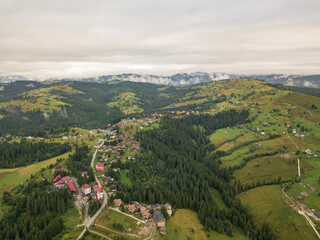 Obraz premium Green slopes of Ukrainian Carpathian mountains in summer. Cloudy morning, low clouds. Aerial drone view.