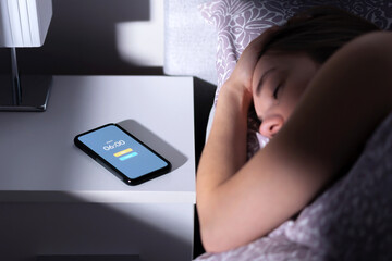 Phone alarm waking up tired sleeping woman in bed at night or morning. Cellphone on table with...