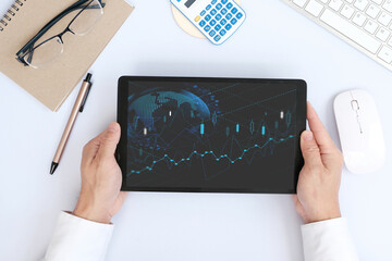 Hand uses a tablet to analyze sales data and an economic graph chart in order to restart business growth and analysing forex trading grap