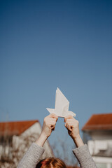 Frieden - junges Mädchen hält Taube aus Papier als Symbol für den Frieden in ihren Händen