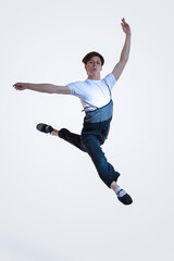 Fototapeta na wymiar Professional Caucasian Male Ballet Dance Performing in Flight With Hands Outspread in Studio Against White Background.