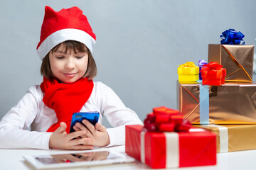 Winsome Caucasian Child Girl In Santa Hat At Laptop for Online Chat Showing Christmas Gift or New Year Present And Using Video Calling By Virtual Chat