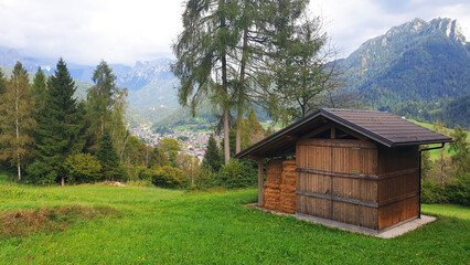 Landscape with a wooden hayloft against the backdrop of the dolomite mountains.