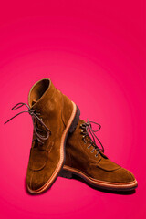 Footwear Ideas. Pair of Tan Brown Suede Split Toe High Boots Closeup With Rubber Sole Placed on One Another Over Pink Red Background.