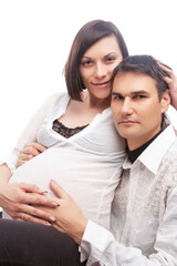 Closeup of Loving Caucasian Couple with Pregnant Wife Woman Interacting While Sitting While Touching Belly Embraced Against White Background.