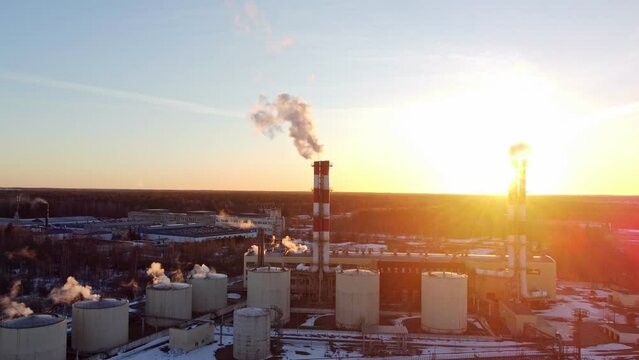 thermal power plant, pipes with smoke against the background of the outgoing sun in winter