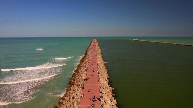 Aerial view of long breakwater of Tampico beach with walking people