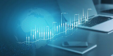 Obraz premium Close up of office desktop with abstract glowing business chart with globe hologram on blurry blue background. Trade, finance and economy concept. Double exposure.