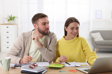 Young couple discussing family budget at table in living room