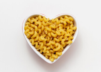 Raw pasta cavatappi in heart bowl.