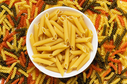 Raw pasta torti texture and penne rigate in bowl